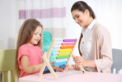 teacher watches over the child as she plays